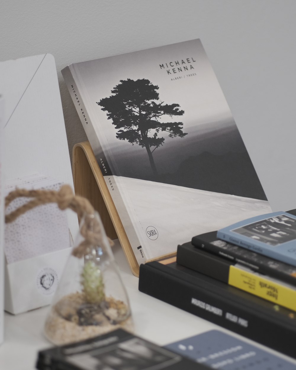 Il libro Alberi di Michael Kenna su un leggio, con riviste fotografiche impilate